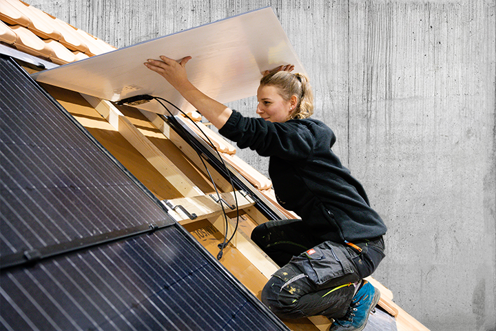 Solarinstallateurin arbeitet auf Steildach und installierte eine Solaranlage Gebäudehülle Schweiz